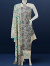 Off white and slate blue Katan silk unstitched suit set hand block printed with stylised swirls and fish motifs in an asymmetric repeat, with teal and charcoal grey accents and fringed edges.